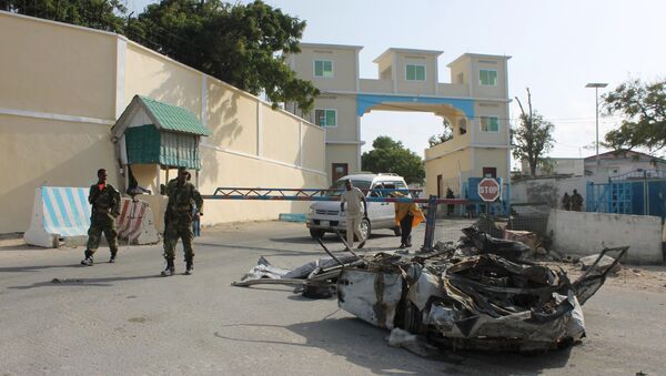 Somali soldiers walk past the wreckage of a car bomb by the main gate outside the presidential palace in Mogadishu (File) - Sputnik Mundo