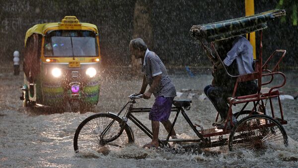 Un conductor de 'rickshaw' durante una fuerte lluvia en Nueva Delhi. - Sputnik Mundo