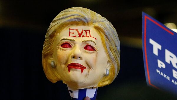 A man holds up a Hillary Clinton mask with the word Evil written across the forehead as Republican presidential nominee Donald Trump speaks at a campaign rally in Phoenix - Sputnik Mundo