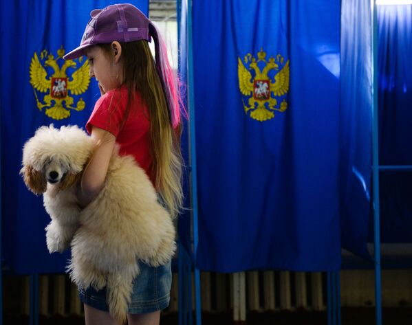 Una niña y su perro, en un colegio electoral en la ciudad rusa de Novosibirsk, durante las elecciones parlamentarias del país eslavo, llevadas a cabo el 18 de septiembre. - Sputnik Mundo