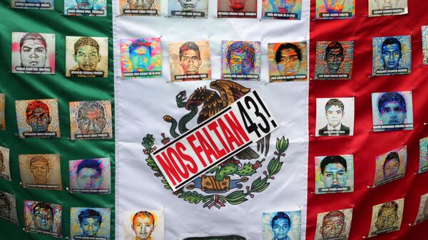 A Mexican flag and some pictures of the 43 missing students is seen in a march to demand justice for the 43 missing students of Ayotzinapa College Raul Isidro Burgos to mark the two-year anniversary of their disappearance in the state of Guerrero, in Mexico City, Mexico, September 26, 2016. - Sputnik Mundo