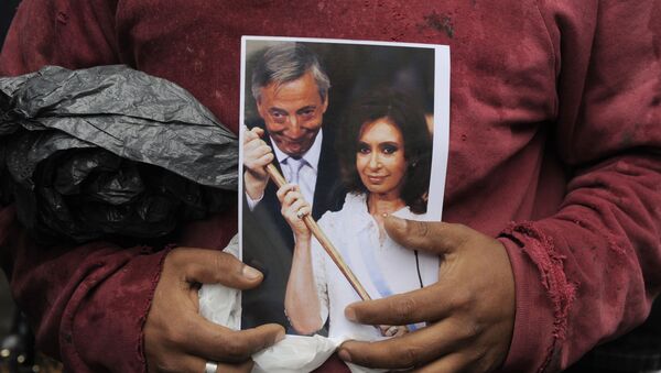 A woman holds a picture of former Argentina's President Nestor Kirchner and his wife, current President Cristina Fernandez, as she waits to see the motorcade carrying the coffin with the remains of the late former president in Buenos Aires, Argentina, Friday, Oct. 29, 2010 - Sputnik Mundo