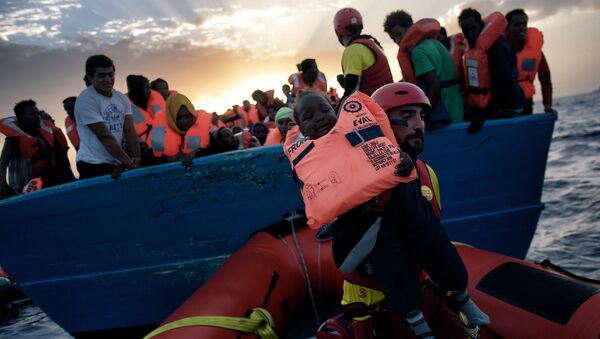 Спасение ребенка с терпящего бедствие судна с мигрантами в Средиземном море - Sputnik Mundo