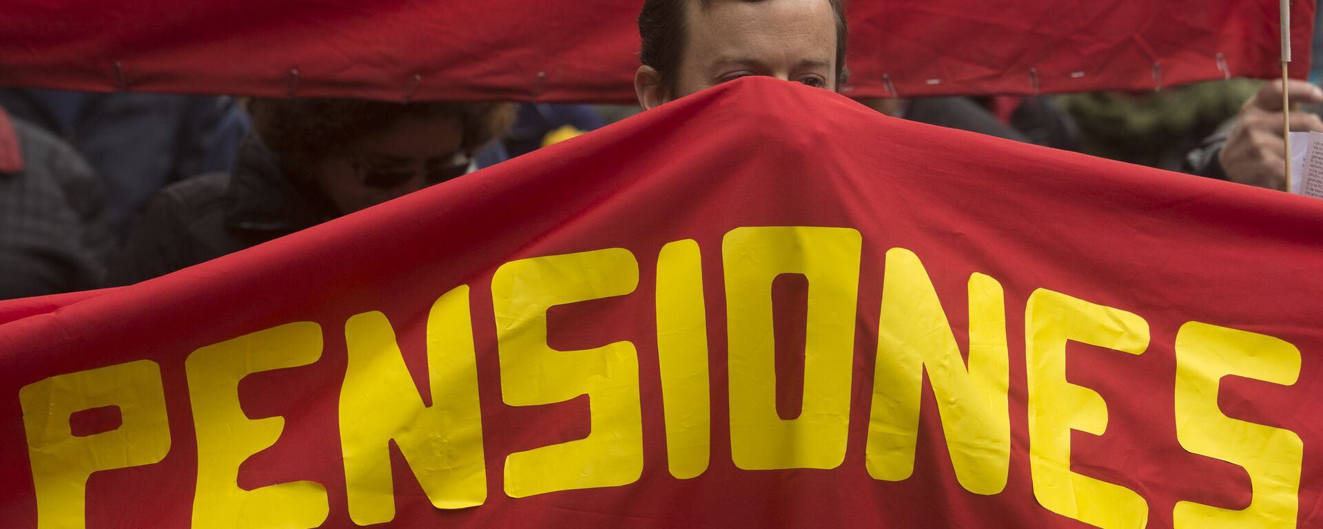 Un trabajador camina detrás de una pancarta que dice: Pensiones durante una marcha en Madrid, España, el miércoles 1 de mayo de 2013. - Sputnik Mundo, 1920, 24.10.2023