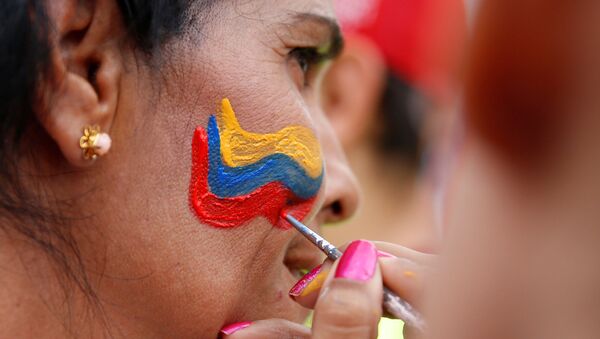 Protesters paint the Venezuelan flag in their face during a rally against Venezuela's President Nicolas Maduro's government in Caracas - Sputnik Mundo