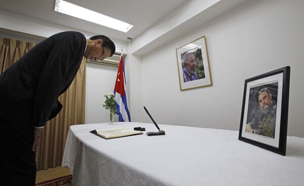 El ex ministro de Relaciones Exteriores de Japón, Keiji Furuya, también miembro de la liga parlamentaria de amistad entre Japón y Cuba, se inclina frente a los retratos de Fidel Castro en la embajada de Cuba en Tokio, Japón. - Sputnik Mundo
