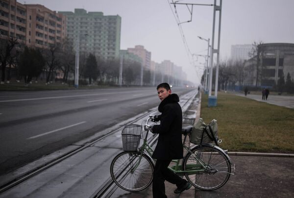Un joven empuja una bicicleta en una calle de la capital norcoreana - Sputnik Mundo