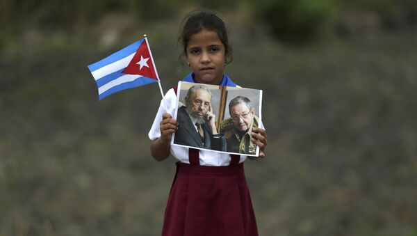 Niña sostiene retratos de los líderes cubanos - Sputnik Mundo