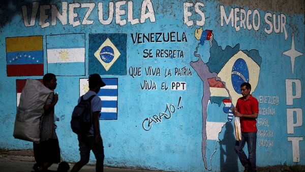 Ciudadanos venezolanos caminan frente a un graffiti referenciando al Mercosur en Caracas, Venezuela - Sputnik Mundo