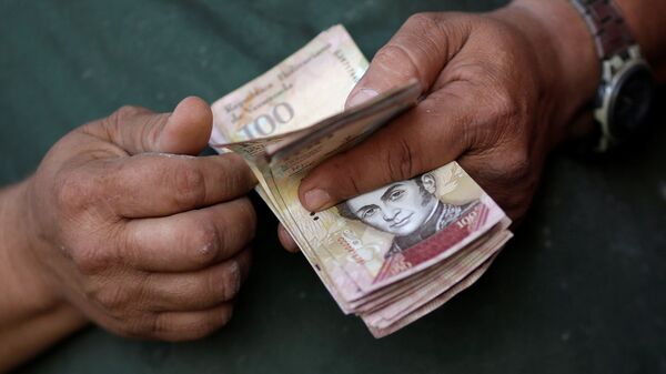 A cashier counts Venezuelan bolivar notes at a street market in downtown Caracas - Sputnik Mundo