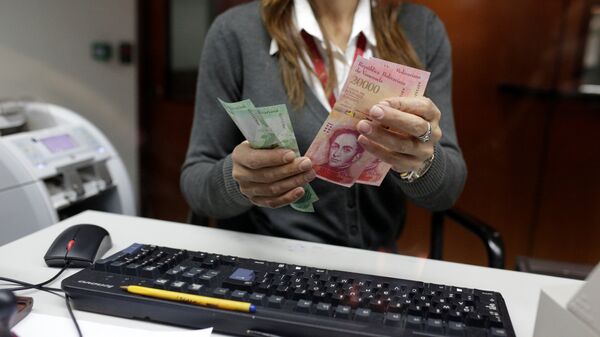 A bank teller counts bolivar banknotes at a Banco de Venezuela branch in Caracas - Sputnik Mundo