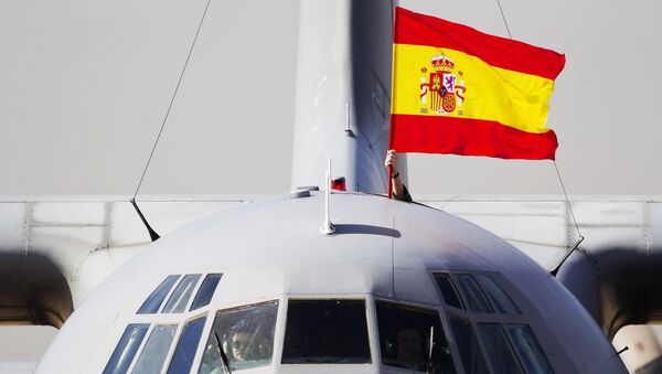 A Spanish flag is waved from a plane carrying some of the 17 tons of silver and gold coins scooped up from a Spanish warship, Nuestra Senora de las Mercedes, that sank during a 1804 gunbattle, after its arrival at the Torrejon De Ardoz military airbase, near Madrid, on Saturday Feb. 25, 2012 - Sputnik Mundo