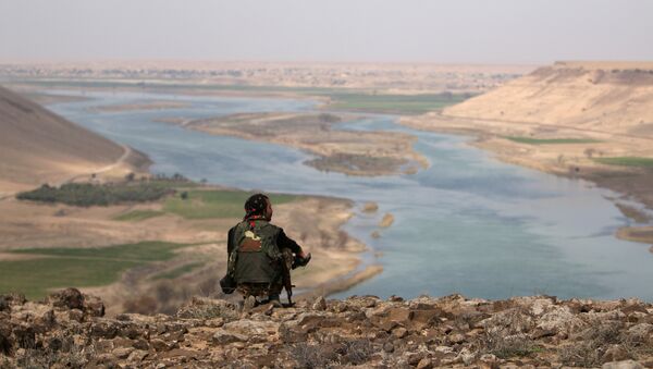 A Syrian Democratic Forces(SDF) fighter rests while looking over the Euphrates River, north of Raqqa city - Sputnik Mundo