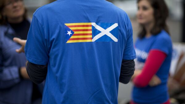 David Aguilar who is visiting Scotland from Catalonia to support the Scottish independence referendum, wears a t-shirt printed with a design showing an estelada Catalan pro-independence flag, left, next to a Scottish Saltire flag as he speaks to passersby in Edinburgh, Scotland, Thursday, Sept. 18, 2014 - Sputnik Mundo