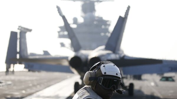 Un miembro de la tripulación de la Marina estadounidense al lado del caza F / A-18 Super Hornet que se prepara para despegar del USS Ronald Reagan (archivo) - Sputnik Mundo