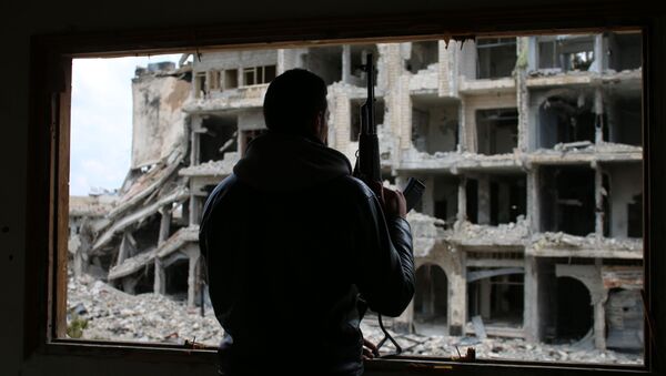 A Syrian rebel fighter stands behind a window in a heavily damaged neighbourhood of Daraa, in southern Syria, on April 2, 2017 - Sputnik Mundo
