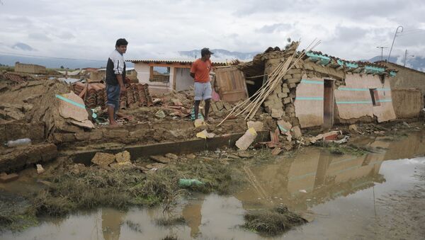 Two men look at collapsed houses after a flood in Churusi-Punata in Cochabamba, Bolivia, Friday, Feb. 7, 2014. The latest report released by Bolivia's Ministry of Defense said the storms plaguing Bolivia since last September has left a momentary balance of dozens of deaths and thousands of families evacuated from their homes. - Sputnik Mundo