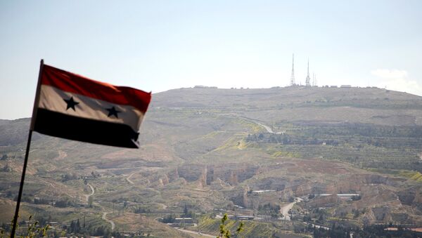 A Syrian national flag flutters as Qasioun mountain is seen in the background from Damascus, Syria April 7, 2017 - Sputnik Mundo