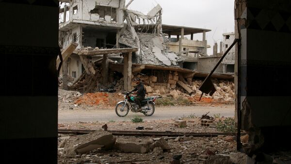 Un hombre monta una motocicleta cerca de los edificios dañados en la zona rebelde en Siria - Sputnik Mundo