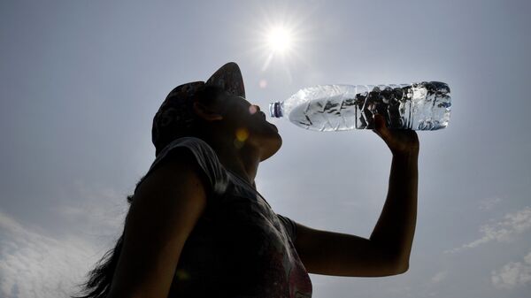 Una mujer bebe agua durante una ola de calor en Europa - Sputnik Mundo