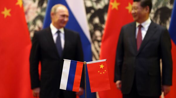 The Russian and Chinese national flags are seen on the table as Russia's President Vladimir Putin (back L) and his China's President Xi Jinping (back R) stand during a signing ceremony at the Diaoyutai State Guesthouse in Beijing on November 9, 2014. - Sputnik Mundo