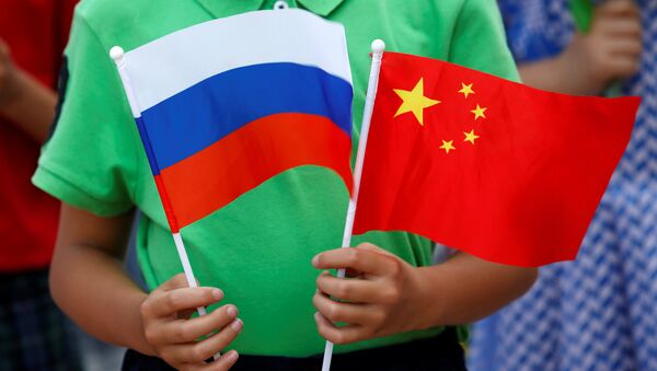 A child holds the national flags of Russia and China prior to a welcoming ceremony for Russian President Vladimir Putin outside the Great Hall of the People in Beijing, China, June 25, 2016 - Sputnik Mundo