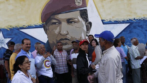La gente venezolana ante una muralla con la imágen del expresidente de Venezuela, Hugo Chávez (archivo) - Sputnik Mundo