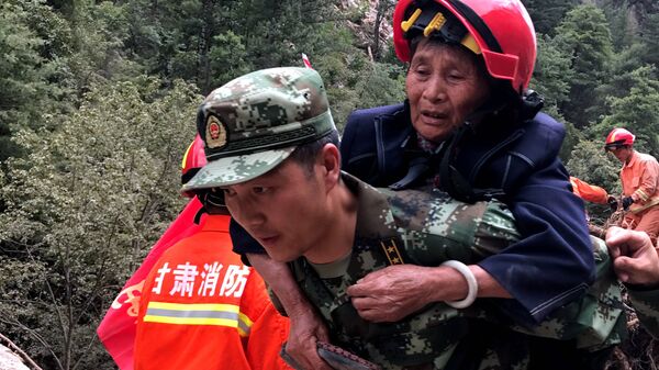 Un rescatista socorre a una mujer afectada por el terremoto en China - Sputnik Mundo