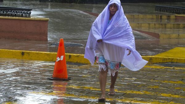 Una mujer se cubre de la lluvia tropical causada por el huracán Franklin - Sputnik Mundo