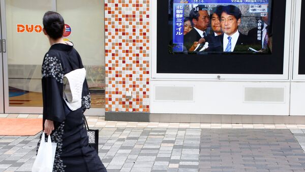 Una japonesa pasa por la pantalla con las noticias sobre el lanzamiento de un misil norcoreano - Sputnik Mundo