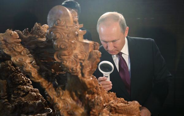 Vladímir Putin, presidente de Rusia, mira a una escultura de madera - Sputnik Mundo