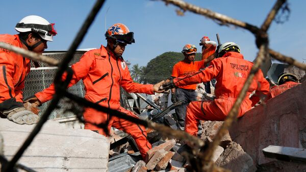 Rescue workers know as Topos Azteca clear the debris of a building damaged in an earthquake that struck the southern coast of Mexico - Sputnik Mundo