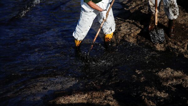 Los obreros limpien la costa de la marea megra - Sputnik Mundo