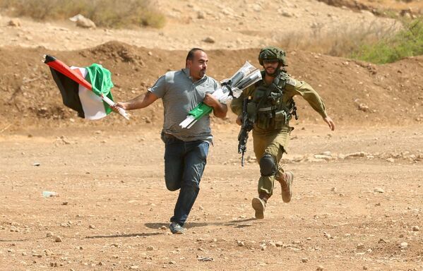 Un soldado israelí persigue a un palestino durante los enfrentamientos en Cisjordania - Sputnik Mundo