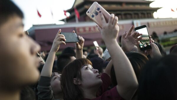 Una joven china sacando una foto con un teléfono móvil en Pekín - Sputnik Mundo