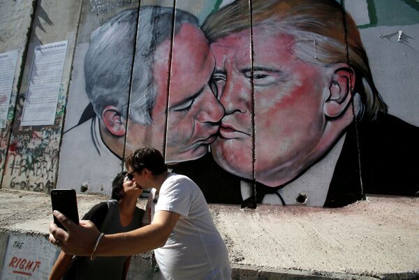 Los turistas se toman fotos cerca del grafiti que muestra al primer ministro israelí, Benjamín Netanyahu, y el presidente de EEUU, Donald Trump, en Belén (Palestina). - Sputnik Mundo