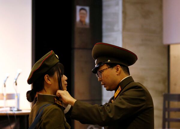 Fanes japoneses de Corea del Norte ajustándose el uniforme del Ejército Popular de Corea frente al retrato del fallecido líder norcoreano Kim Jong-il. - Sputnik Mundo