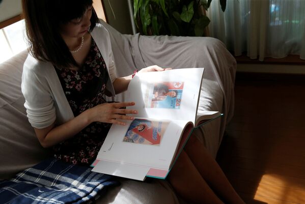 Chunhun, la líder del club de fanes 'Sengun-joshi' ('Chicas militares ante todo'), observando un álbum con imágenes de arte norcoreano. - Sputnik Mundo
