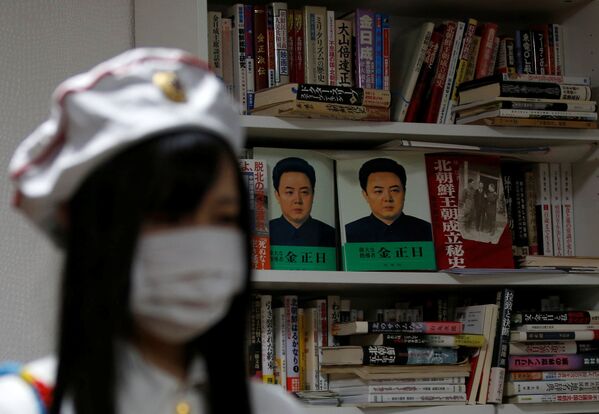 Miembro del club de fanes de Corea del Norte ante un estante de libros de la RPDC. - Sputnik Mundo