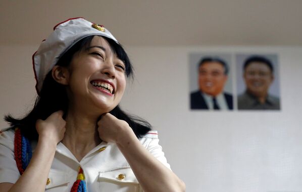 Chunhun, la líder del club de fanes 'Sengun-joshi' ('Chicas militares ante todo'), sonríe frente a los retratos del fundador de la RPDC, Kim Il-sung, y del fallecido líder norcoreano Kim Jong-il. - Sputnik Mundo
