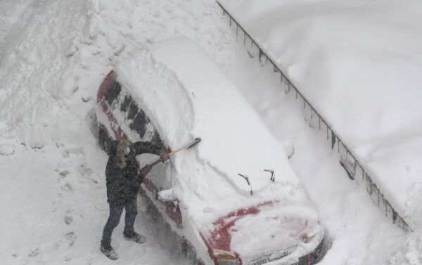 Un hombre está limpiado su auto de la nieve en Moscú - Sputnik Mundo