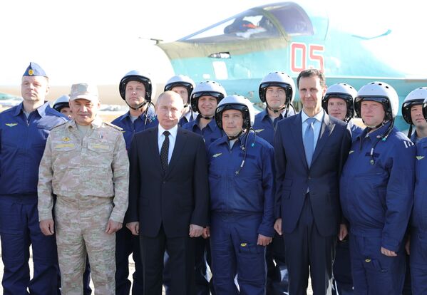 El presidente de Rusia, Vladímir Putin, el presidente de Siria, Bashar Asad, y el ministro de Defensa ruso, Serguéi Shoigú, fotografiados con los militares rusos durante una visita a la base aérea de Hmeymim, en Siria - Sputnik Mundo