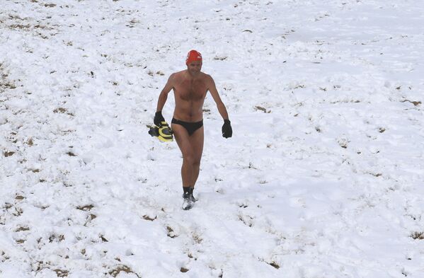 Un nadador camina a lo largo de la playa nevada de Biarritz después de zambullirse en el océano Atlántico. - Sputnik Mundo