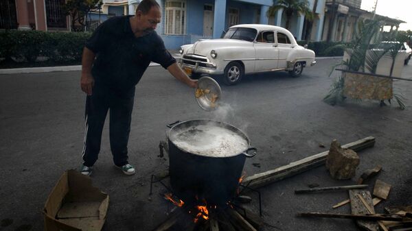 Un hombre prepara caldosa en la calle por el Aniversario de los CDR en Cuba - Sputnik Mundo