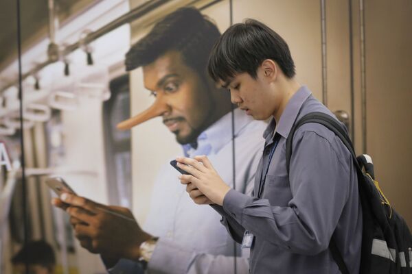 Un joven junto a un anuncio en el que se prohíbe la difusión noticias falsas en una estación de Kuala Lumpur (Malasia). - Sputnik Mundo