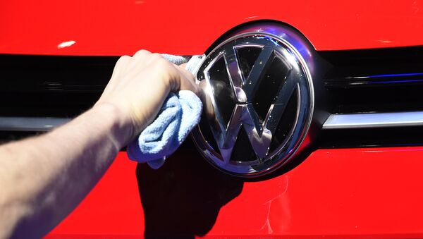 Un hombre puliendo el logotipo del automóvil del fabricante de automóviles alemán Volkswagen - Sputnik Mundo