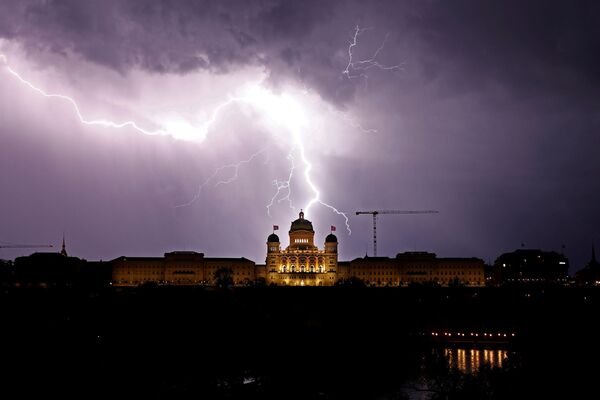 Un relámpago en el cielo sobre el Palacio Federal de Berna, en Suiza. - Sputnik Mundo