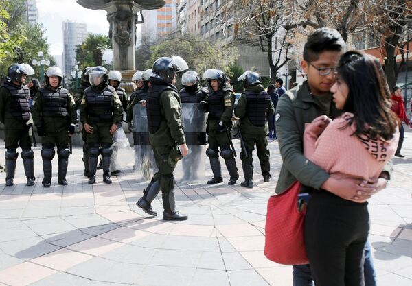 Пара стоит рядом с полицейскими, которые готовятся к протестам студентов университета UPEA в Ла-Пасе, Боливия - Sputnik Mundo