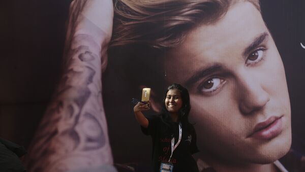 Una fan del cantante canadiense Justin Bieber se hace un selfi delante de una fotografía del astro - Sputnik Mundo
