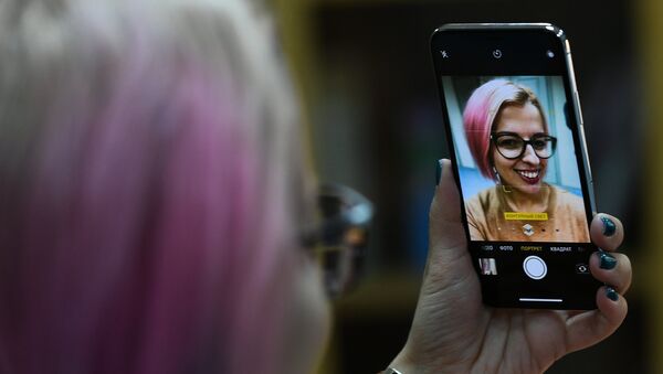 Una chica se hace una selfi con un iPhone X - Sputnik Mundo